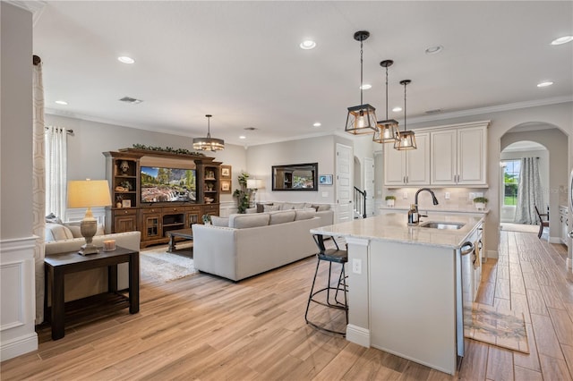 10180 Merrymeeting Bay Dr, Winter Garden, FL 34787 - kitchen with arched walkways, open floor plan, light wood-style flooring, light stone countertops, and recessed lighting