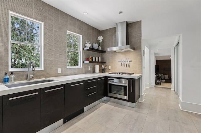 213 Phillips Pl, Orlando, FL 32806 - kitchen with wall chimney exhaust hood, appliances with stainless steel finishes, dark cabinetry, light countertops, and tasteful backsplash
