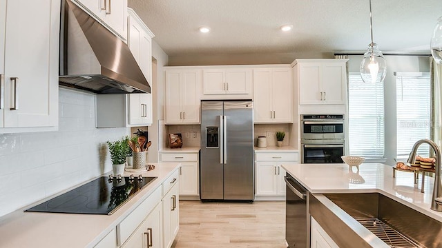 5277 Bowspirit Way, Saint Cloud, FL 34771 - kitchen with appliances with stainless steel finishes, under cabinet range hood, backsplash, white cabinetry, and decorative light fixtures