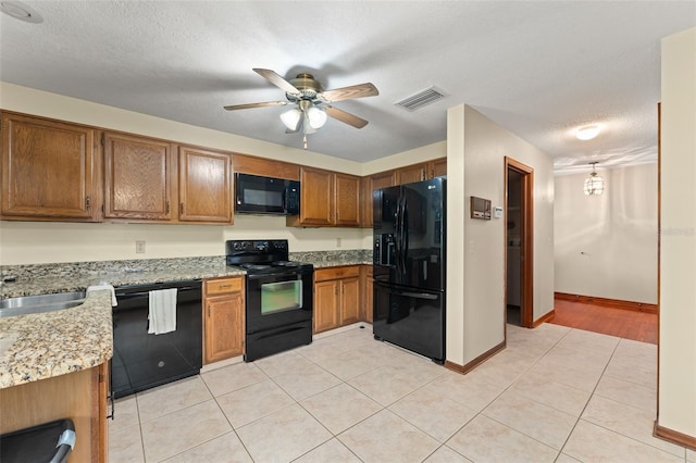 3310 Tall Timber Dr, Orlando, FL 32812 - kitchen with black appliances, ceiling fan, brown cabinets, light tile patterned floors, and a textured ceiling