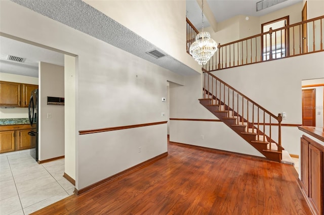 3310 Tall Timber Dr, Orlando, FL 32812 - unfurnished living room featuring stairs, a chandelier, light wood finished floors, and a high ceiling