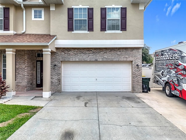 238 Hunt St, Clermont, FL 34711 - view of front of home featuring brick siding, a garage, stucco siding, and driveway