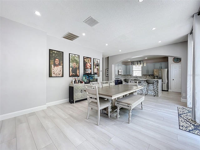 238 Hunt St, Clermont, FL 34711 - dining area with arched walkways, light wood-type flooring, recessed lighting, and a textured ceiling