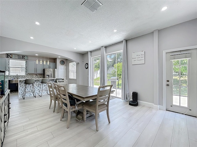 238 Hunt St, Clermont, FL 34711 - dining room featuring arched walkways, recessed lighting, a textured ceiling, healthy amount of natural light, and light wood finished floors