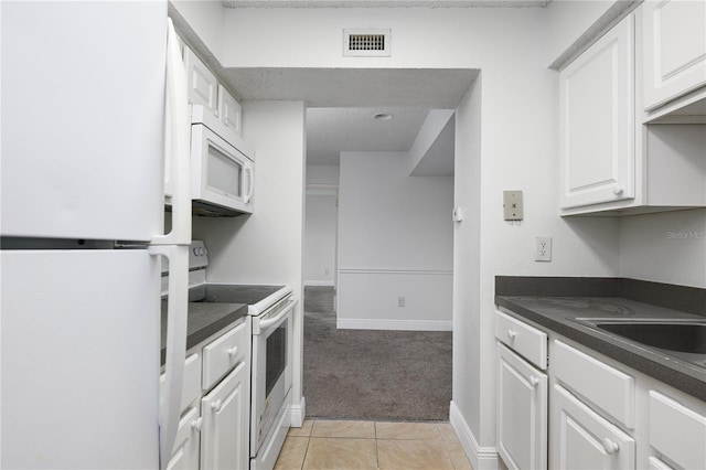 3700 Idlebrook Cir Unit 200, Casselberry, FL 32707 - kitchen with white appliances, light colored carpet, dark countertops, white cabinetry, and light tile patterned floors