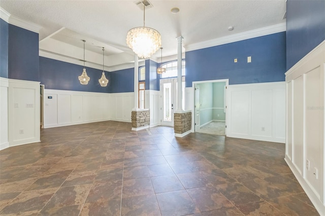 1818 W Cobblestone Ln, Saint Augustine, FL 32092 - unfurnished living room featuring a decorative wall, decorative columns, a chandelier, wainscoting, and crown molding