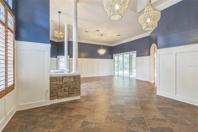 1818 W Cobblestone Ln, Saint Augustine, FL 32092 - unfurnished living room featuring a decorative wall, a chandelier, ornamental molding, ornate columns, and stone finish floors