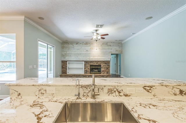 1818 W Cobblestone Ln, Saint Augustine, FL 32092 - kitchen with ceiling fan, a textured ceiling, a fireplace, ornamental molding, and light stone counters