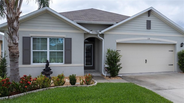 138 Old Mill Pond Rd, Edgewater, FL 32141 - view of front facade with driveway, a garage, stucco siding, and roof with shingles