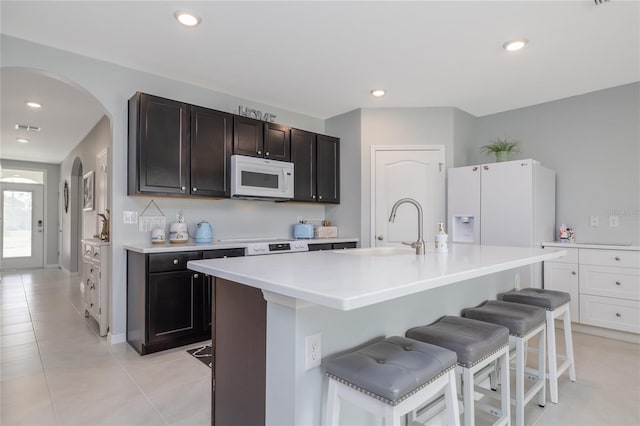 138 Old Mill Pond Rd, Edgewater, FL 32141 - kitchen with white appliances, arched walkways, a breakfast bar area, light countertops, and light tile patterned floors