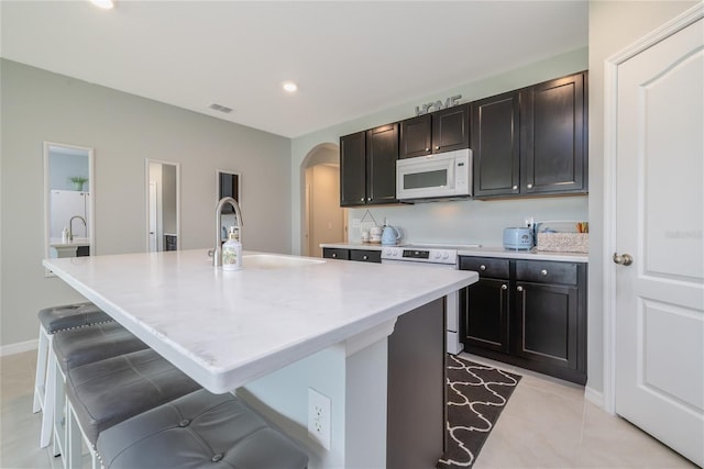 138 Old Mill Pond Rd, Edgewater, FL 32141 - kitchen featuring white appliances, arched walkways, a kitchen island with sink, light countertops, and light tile patterned floors
