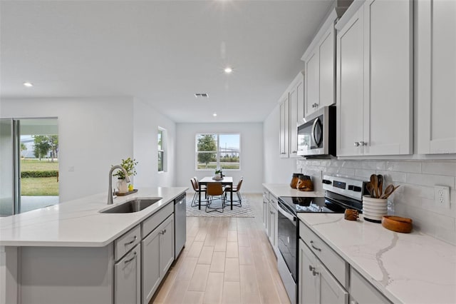 2627 Ginseng Ivy St, Apopka, FL 32703 - kitchen with appliances with stainless steel finishes, recessed lighting, tasteful backsplash, a center island with sink, and light stone countertops