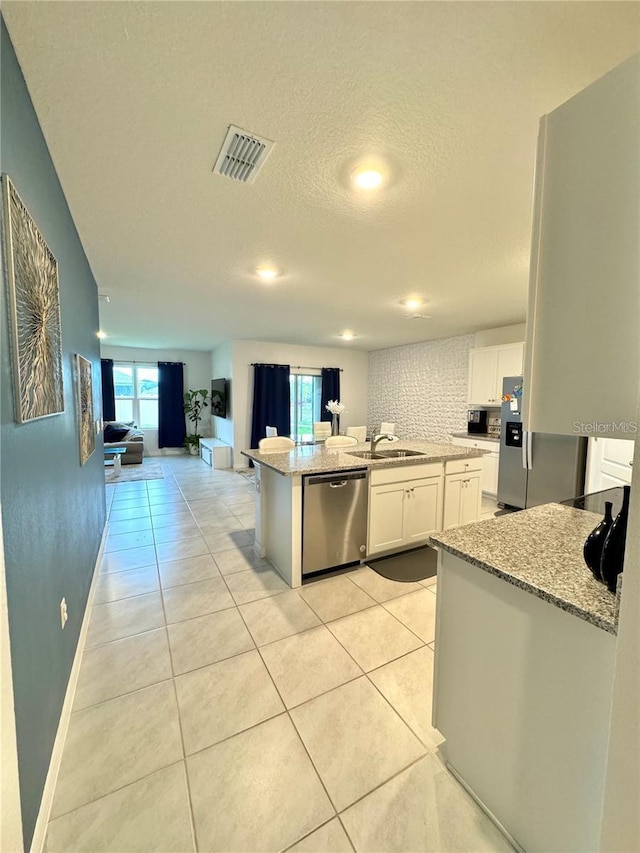 577 Talisi Loop, Saint Cloud, FL 34771 - kitchen with stainless steel appliances, open floor plan, white cabinets, light stone counters, and light tile patterned flooring
