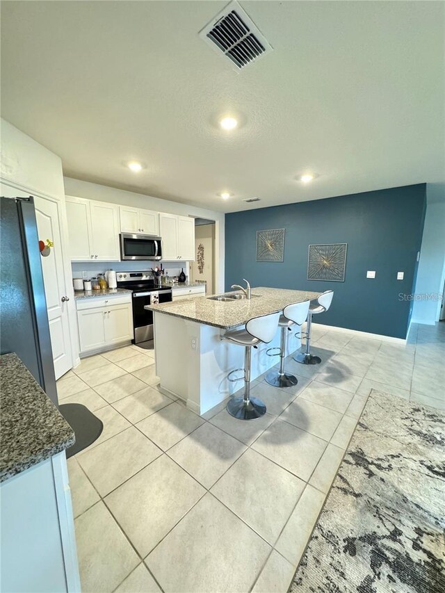 577 Talisi Loop, Saint Cloud, FL 34771 - kitchen featuring appliances with stainless steel finishes, white cabinets, light tile patterned floors, stone counters, and recessed lighting