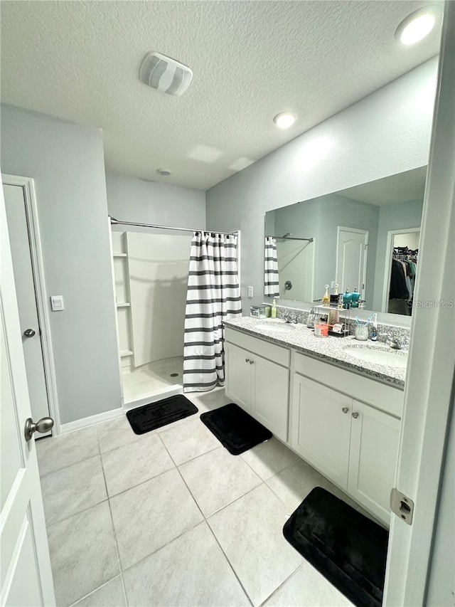 577 Talisi Loop, Saint Cloud, FL 34771 - bathroom with a stall shower, a textured ceiling, double vanity, a spacious closet, and tile patterned floors