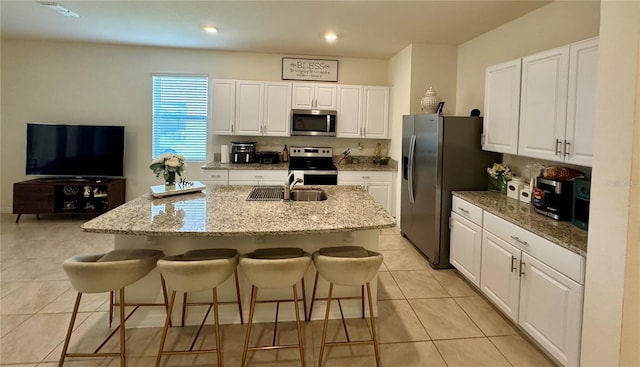 1314 Isleta Loop, Kissimmee, FL 34741 - kitchen with appliances with stainless steel finishes, white cabinets, a center island with sink, a breakfast bar area, and light tile patterned flooring