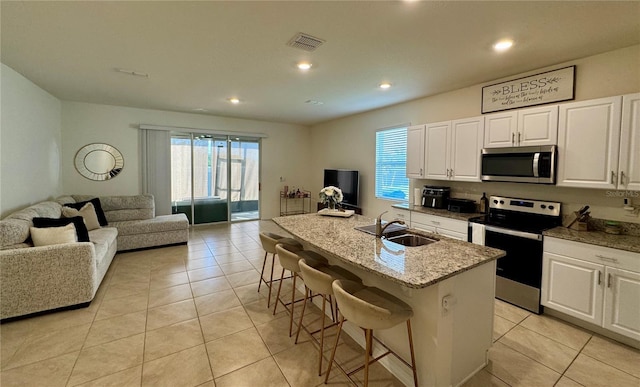1314 Isleta Loop, Kissimmee, FL 34741 - kitchen featuring stainless steel appliances, open floor plan, light stone countertops, white cabinets, and a breakfast bar area