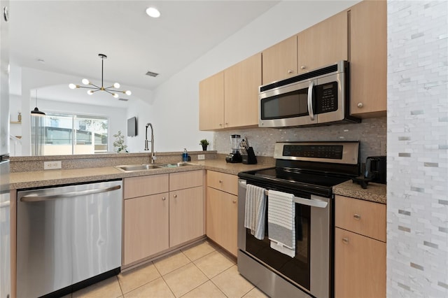 1176 S Beach Cir, Kissimmee, FL 34746 - kitchen featuring appliances with stainless steel finishes, light brown cabinets, a chandelier, backsplash, and light tile patterned floors