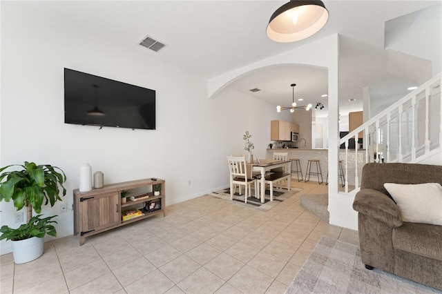 1176 S Beach Cir, Kissimmee, FL 34746 - living area featuring light tile patterned floors, arched walkways, stairs, and a chandelier