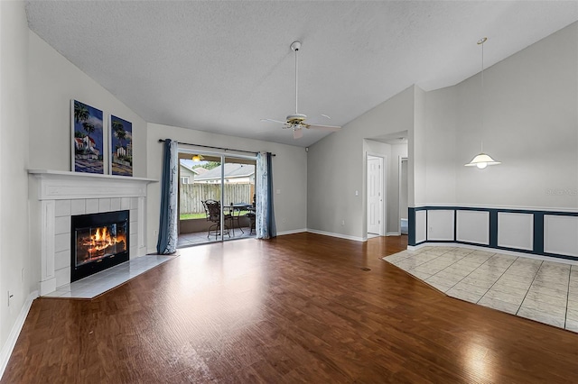 1326 Hampshire Place Cir, Altamonte Springs, FL 32714 - unfurnished living room featuring lofted ceiling, wood finished floors, a tiled fireplace, ceiling fan, and a textured ceiling
