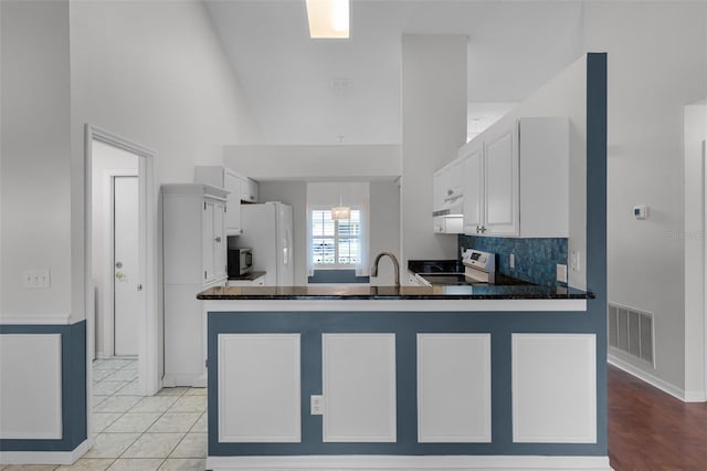 1326 Hampshire Place Cir, Altamonte Springs, FL 32714 - kitchen with range with electric stovetop, freestanding refrigerator, high vaulted ceiling, white cabinetry, and a peninsula
