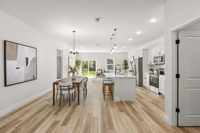 1970 SW 160th Pl, Ocala, FL 34473 - kitchen featuring appliances with stainless steel finishes, recessed lighting, white cabinetry, light wood-style flooring, and a kitchen bar