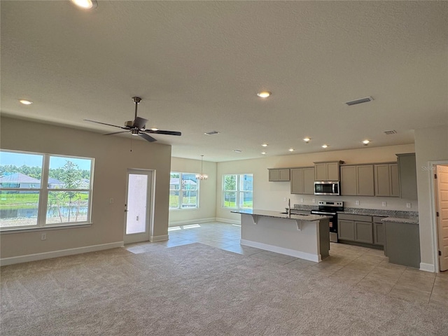 4113 Sagefield Dr, Harmony, FL 34773 - kitchen featuring appliances with stainless steel finishes, gray cabinets, light colored carpet, open floor plan, and a breakfast bar area