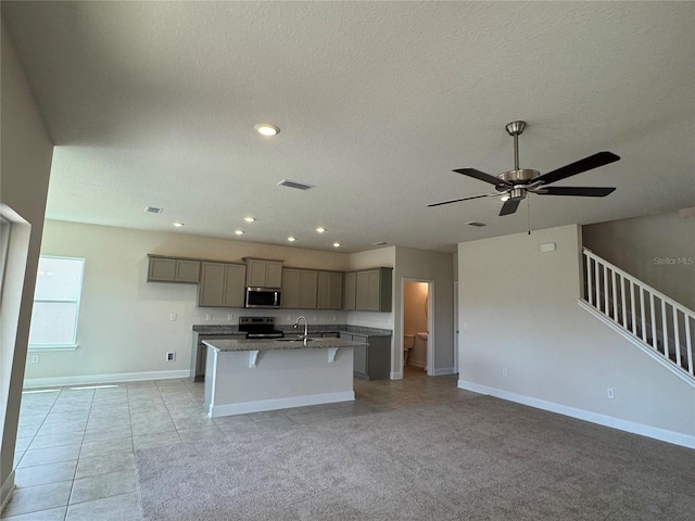 4113 Sagefield Dr, Harmony, FL 34773 - kitchen featuring stainless steel microwave, range with electric stovetop, gray cabinetry, a kitchen island with sink, and open floor plan