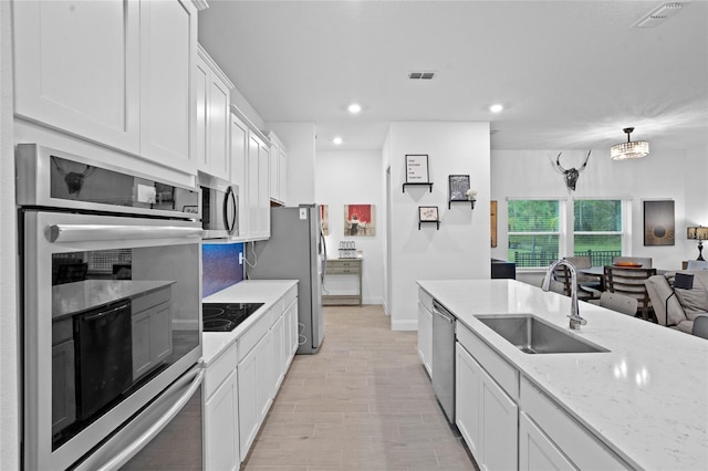 2149 Raglan Cir, Ormond Beach, FL 32174 - kitchen with stainless steel appliances, white cabinets, light stone counters, open floor plan, and recessed lighting