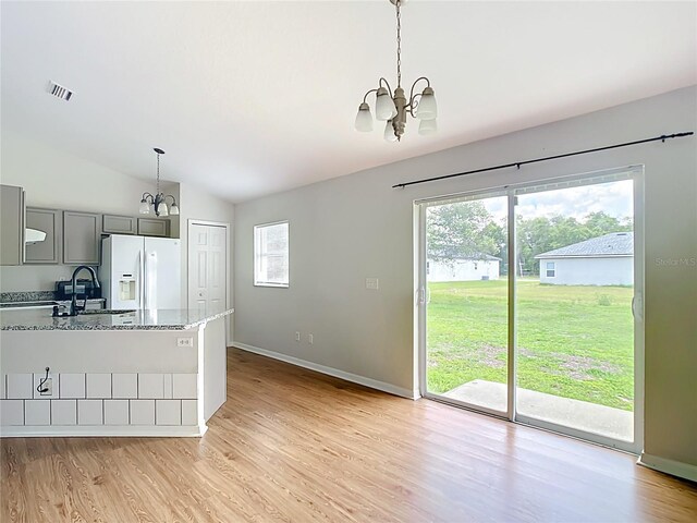 14939 SW 46th Cir, Ocala, FL 34473 - kitchen with white fridge with ice dispenser, a chandelier, gray cabinets, light wood finished floors, and lofted ceiling