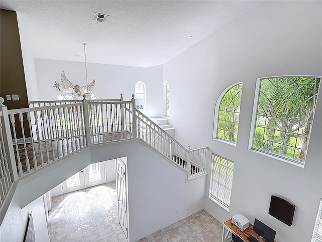 2460 The Oaks Blvd, Kissimmee, FL 34746 - stairs with a chandelier, a textured ceiling, and a high ceiling