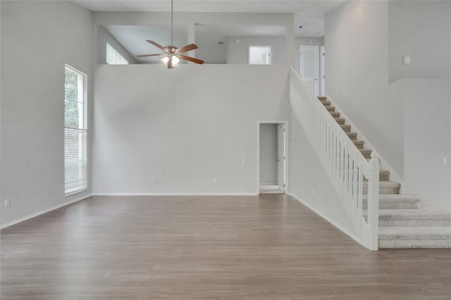2262 Stonehedge Loop, Kissimmee, FL 34743 - unfurnished living room featuring a ceiling fan, wood finished floors, a towering ceiling, and stairway