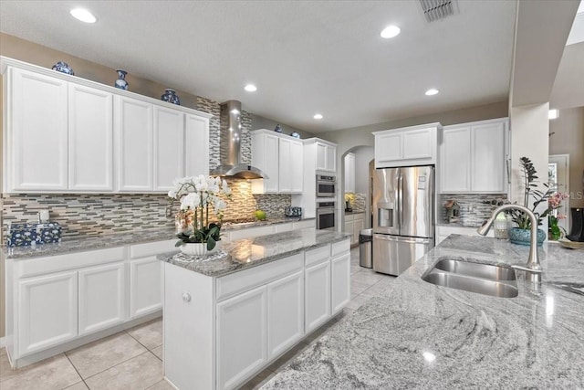15264 Shonan Gold Dr, Winter Garden, FL 34787 - kitchen featuring stainless steel appliances, wall chimney range hood, arched walkways, backsplash, and a center island