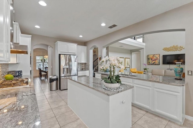 15264 Shonan Gold Dr, Winter Garden, FL 34787 - kitchen with appliances with stainless steel finishes, arched walkways, a kitchen island, tasteful backsplash, and white cabinetry