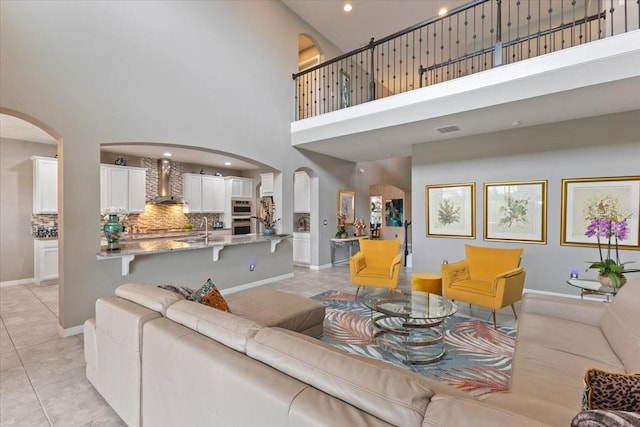 15264 Shonan Gold Dr, Winter Garden, FL 34787 - living room featuring arched walkways, a high ceiling, light tile patterned flooring, and recessed lighting