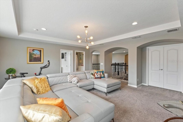 15264 Shonan Gold Dr, Winter Garden, FL 34787 - carpeted living room with arched walkways, a raised ceiling, a chandelier, recessed lighting, and a textured ceiling