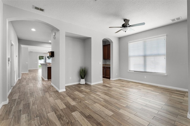 6539 Chagford Ln, Windermere, FL 34786 - unfurnished living room featuring ceiling fan, arched walkways, light wood finished floors, a textured ceiling, and recessed lighting