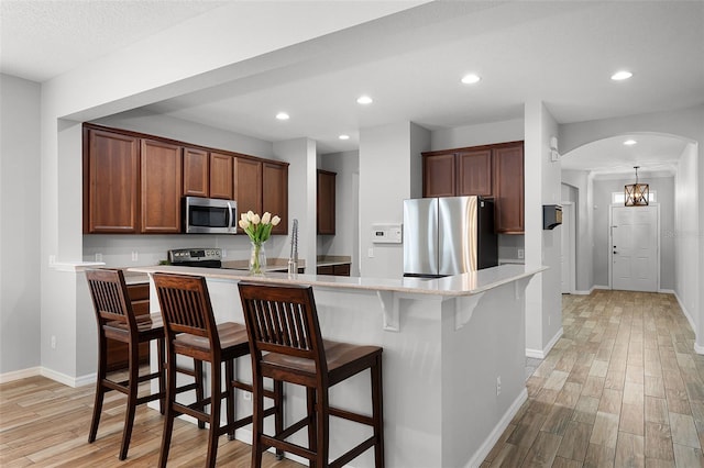 6539 Chagford Ln, Windermere, FL 34786 - kitchen featuring stainless steel appliances, light wood finished floors, light countertops, a breakfast bar area, and arched walkways