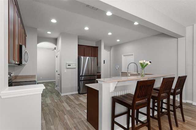 6539 Chagford Ln, Windermere, FL 34786 - kitchen with appliances with stainless steel finishes, light wood finished floors, a breakfast bar area, arched walkways, and recessed lighting