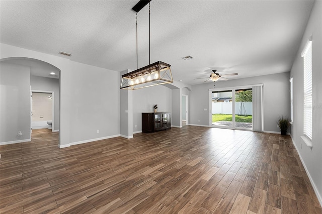 6539 Chagford Ln, Windermere, FL 34786 - unfurnished living room with arched walkways, ceiling fan, wood finished floors, and a textured ceiling