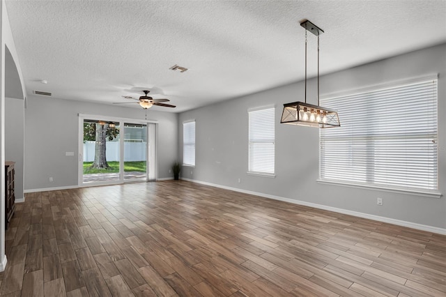 6539 Chagford Ln, Windermere, FL 34786 - unfurnished living room with a textured ceiling, wood finished floors, a ceiling fan, and a chandelier