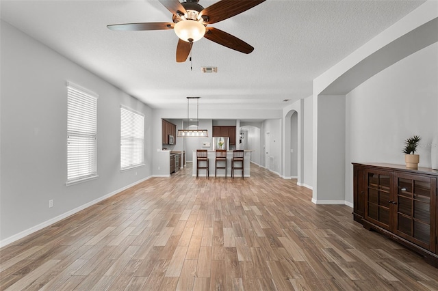 6539 Chagford Ln, Windermere, FL 34786 - unfurnished living room with a ceiling fan, light wood-style flooring, arched walkways, and a textured ceiling
