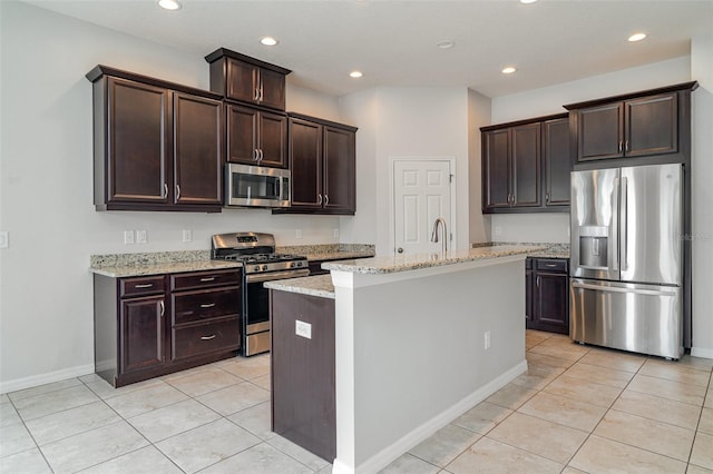 11307 Grand Park Ave, Riverview, FL 33578 - kitchen featuring stainless steel appliances, light tile patterned floors, dark brown cabinetry, light stone countertops, and recessed lighting