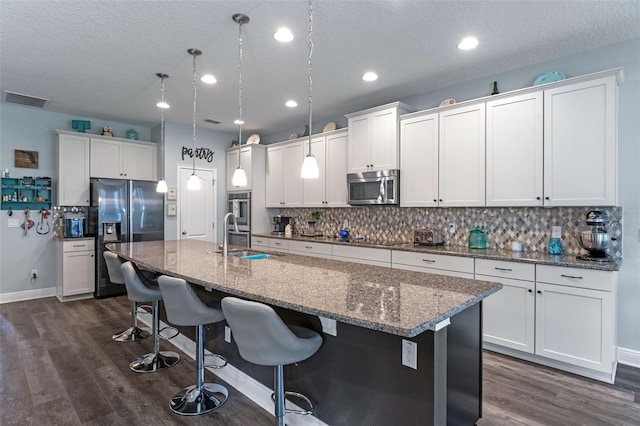 1005 Thunderhead Ln, Minneola, FL 34715 - kitchen with appliances with stainless steel finishes, tasteful backsplash, an island with sink, dark wood-style flooring, and a textured ceiling