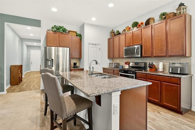 1559 Bayfront Park Aly, Winter Garden, FL 34787 - kitchen featuring appliances with stainless steel finishes, a kitchen island with sink, a breakfast bar area, tasteful backsplash, and recessed lighting