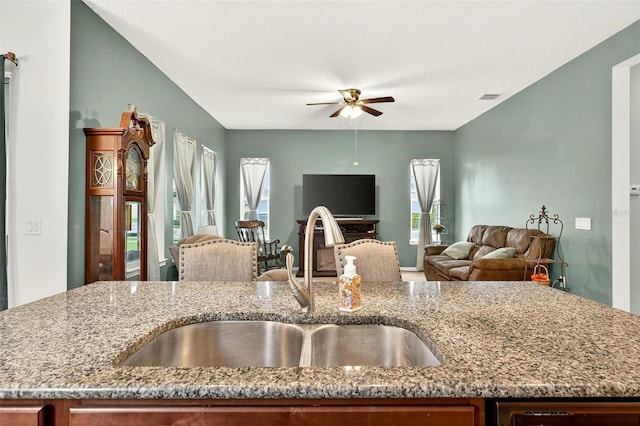1559 Bayfront Park Aly, Winter Garden, FL 34787 - kitchen with open floor plan, light stone counters, ceiling fan, and brown cabinetry