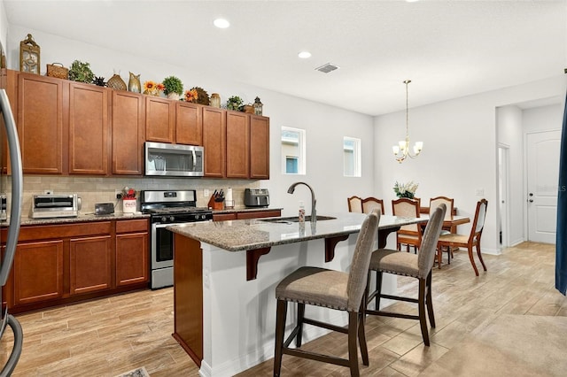 1559 Bayfront Park Aly, Winter Garden, FL 34787 - kitchen with appliances with stainless steel finishes, a kitchen breakfast bar, light wood-type flooring, brown cabinets, and recessed lighting