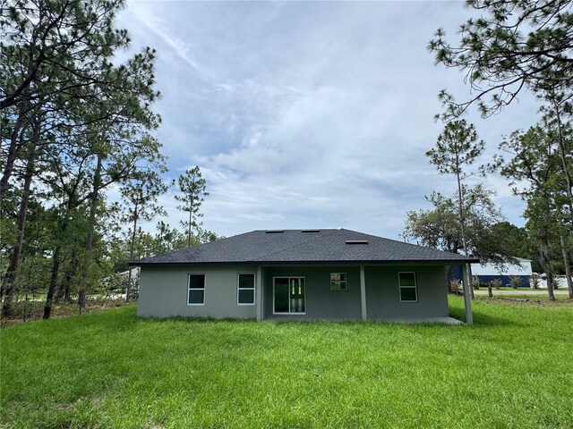 2011 W Tacoma Dr, Citrus Springs, FL 34434 - rear view of property with stucco siding, a yard, and a shingled roof