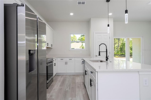 2011 W Tacoma Dr, Citrus Springs, FL 34434 - kitchen featuring stainless steel appliances, light wood-style floors, an island with sink, white cabinets, and hanging light fixtures