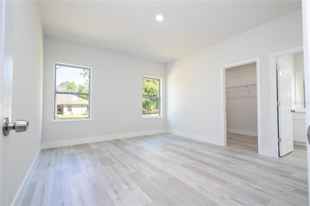 2011 W Tacoma Dr, Citrus Springs, FL 34434 - unfurnished bedroom featuring multiple windows, light wood finished floors, a walk in closet, recessed lighting, and a closet